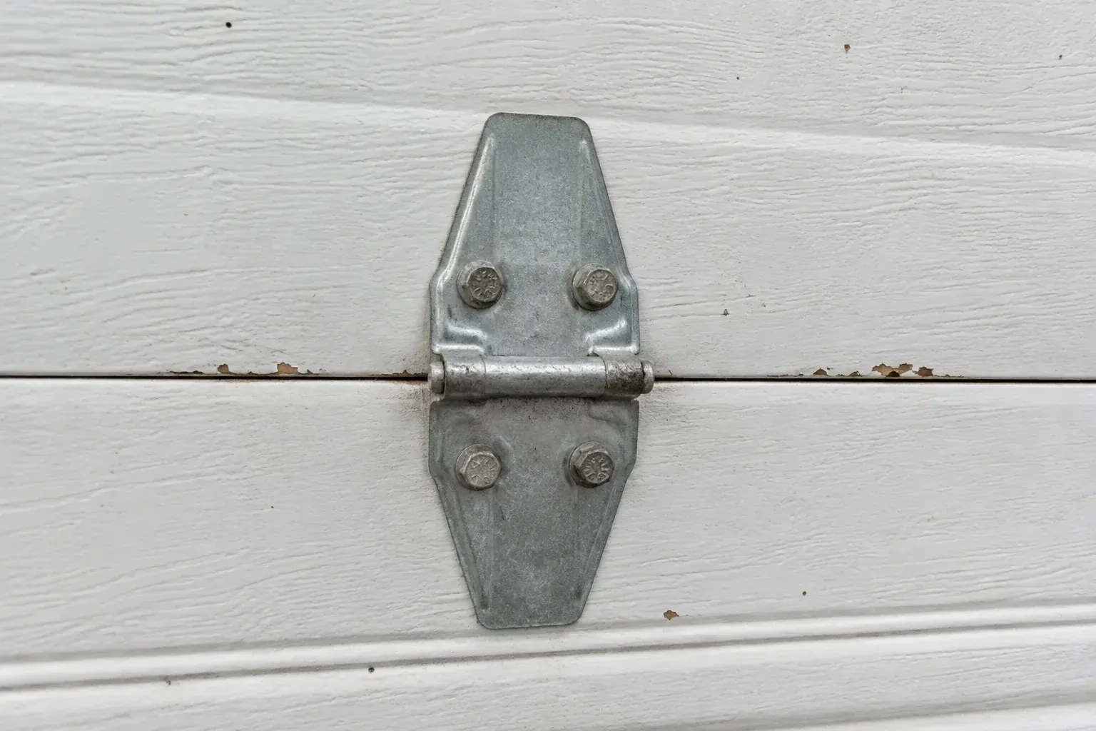 Metal center hinge across a seam in a white sectional garage door. — Garage Door Hinge Replacement, East Gwillimbury